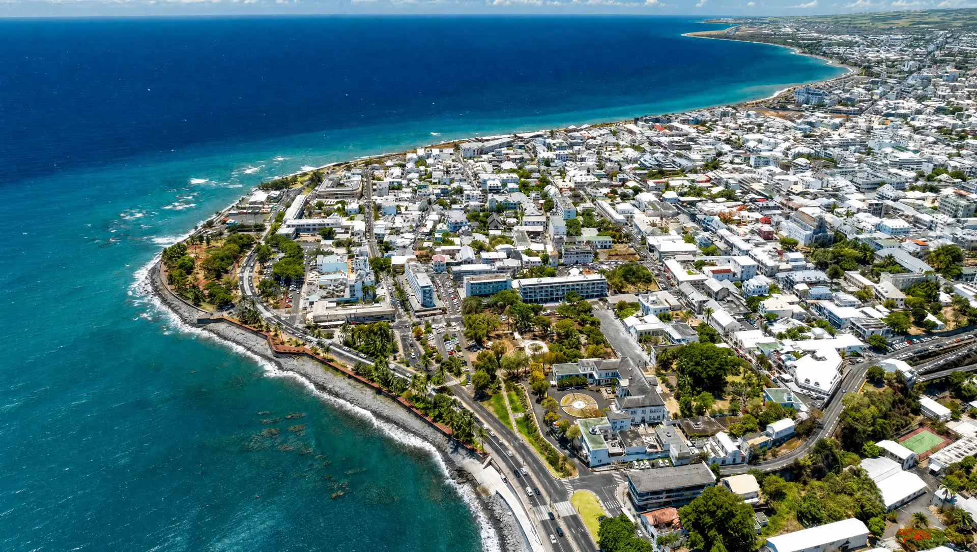 Vue aérienne d'une ville du littoral de La Réunion, front de mer et océan Indien. Image générée par IA.